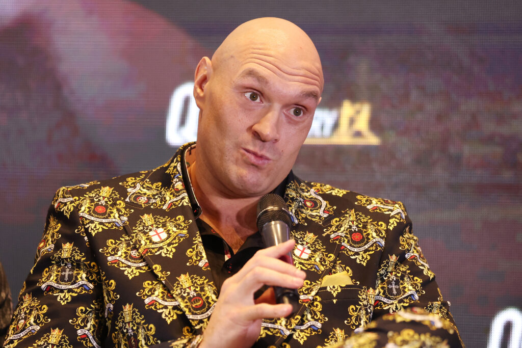 Tyson Fury holds a microphone on stage for the press conference for the fight against Derek Chisora.