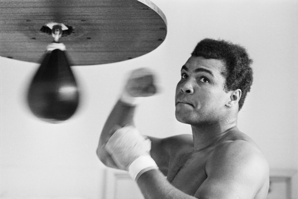 Muhammad Ali hitting a speed bag while stare intently at in